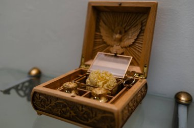 Vaftiz sırasında vaftiz etmek için profesyonel bir dini çantanın yakın çekimi. Altın petrol kapaklarında oyulmuş bir güvercin ve evdeki parlak bir kilisenin arka planında bir sünger var.