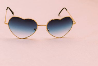 Pembe arka planda kalp şeklinde güneş gözlükleri