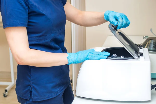 Doctor works with a plasma therapy centrifuge. Plasma therapy