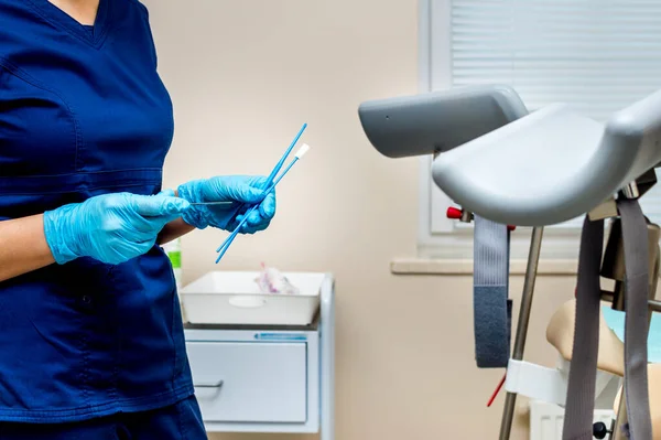 Jinekolog bir kadından test almak için aletler tutuyor. Jinekoloğun ofisi.