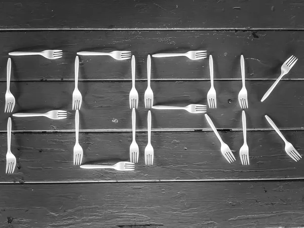 Alfabet widelec wykonane z plastikowych widelców na drewnianym stole w czerni i bieli — Zdjęcie stockowe