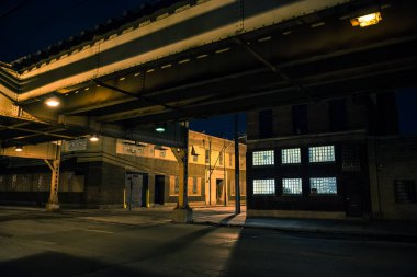 Yükseltilmiş CTA tren rayları, antika endüstriyel depoları ve fabrikaları olan karanlık ve ürkütücü Chicago şehir sokak manzarası.