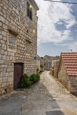Güneşli, dar bir kaldırım taşı sokak rüzgarı tahtadan kepenkleri ve kiremitli çatıları olan tarihi taş evler arasında sakin, kırsal bir köy atmosferi ve zamansız mimari cazibeyi yakalıyor.