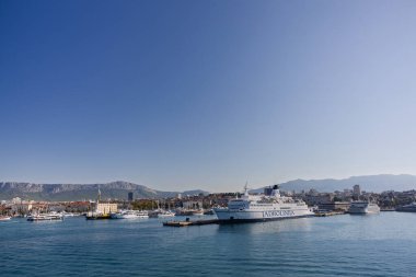 BÖLÜM, CROATIA, 09.06.2020: feribot açık mavi gökyüzünün altında yemyeşil tepelerle çevrili kıyı kasabasının limanına yanaştı.