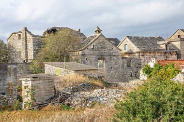 Sessiz bir köyde geleneksel taş evler, kuru taş duvarlar ve sonbahar ağaçlarının olduğu sakin bir kırsal alan. Bulutlu gökyüzü, kırsal yaşam, miras, seyahat veya gayrimenkul hikayeleri için ideal ruh halini ekler..
