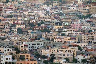 Yoğun bir şekilde kalabalık bir kasabanın dağlık zemin üzerindeki bir yamacın karmaşık bir görüntüsü. Bu pitoresk ortam, şehir mimarisi ile doğal elementleri birleştirerek, insan yerleşiminin ve yamaçtaki çevrenin uyumlu bir karışımını gösteriyor..