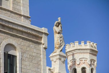 Karmaşık bir şekilde oyulmuş mavi gökyüzünün mimarinin detaylarını artırdığı tarihi bir binanın taş cephesi..