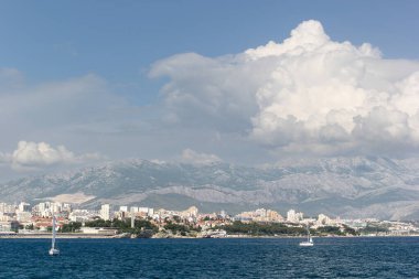 Split 'in deniz manzarası, tarihi işaretler, palmiye çizgili gezinti alanı ve berrak mavi gökyüzünün altındaki manzaralı dağ manzarası..