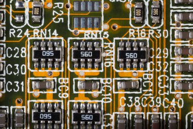 Elektronik bileşenleri titizlikle bir devre kartında gösteren makro bir çekim. Görüntü, modern teknoloji ve hassas mühendisliği temsil eden rezistanslar, mikroçipler ve devre yolları da dahil olmak üzere karmaşık tasarımı vurguluyor..