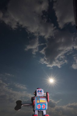Arkasında gökyüzü olan klasik oyuncak robot. Yapay zeka konsepti. Karanlık ortam.