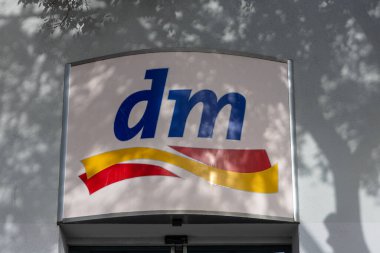 SPLIT, CROATIA, 10.25.2025: Süpürücü sarı ve kırmızı kurdele motifli mavi 'dm' logosunu gösteren bir mağaza levhası. Bu perakende markalaşma görüntüsü modern markalaşma, tabela ve karşılayıcı bir alışveriş ortamını yakalıyor..