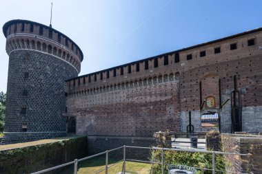 Kuru hendeğe tepeden bakan tuğladan bir kale duvarının yanında uzun yuvarlak bir taş kule duruyor. Parlak gün ışığı antik taş ustası ve tarihi kaleleri vurguluyor.