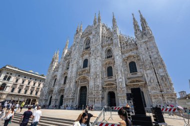 MILAN, ITALY, 06.19.2025: Gotik Duomo heykelleri etrafındaki Milano tarihi meydanı turistler, mimari ve büyük taş işleri sergiliyor. İtalya 'da aydınlık bir gün, ünlü bir kent simgesi etrafında kültür, miras ve şehir yaşamını yakalıyor..