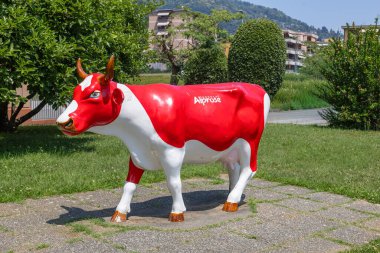 CASLANO, SWitzERLAND, 06.20.2025: parlak kırmızı ve beyaz inek heykeli. Etkileşimli sergi ve çikolata imalatı tarihi ve Çikolata Alprose 'un 1957' den beri başarı öyküsü hakkında her şey..