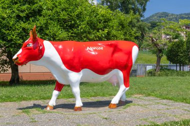 CASLANO, SWitzERLAND, 06.20.2025: parlak kırmızı ve beyaz inek heykeli. Etkileşimli sergi ve çikolata imalatı tarihi ve Çikolata Alprose 'un 1957' den beri başarı öyküsü hakkında her şey..