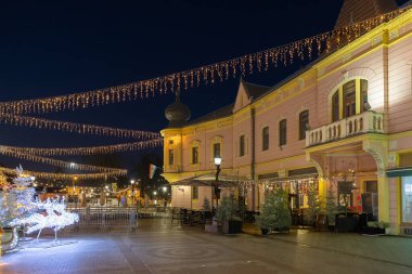 Vinkovci 'deki Advent etkinliği sırasında Vinkovci' deki yaya bölgesini gösteriyor. Mavi saatte Avrupa 'nın şenlikli sokak sahnesi. Pembe bir köşe binası, sicim lambaları ve büyük tarihi bir ön cephe..