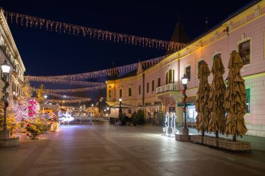 Vinkovci 'deki Advent etkinliği sırasında Vinkovci' deki yaya bölgesini gösteriyor. Mavi saatte Avrupa 'nın şenlikli sokak sahnesi. Pembe bir köşe binası, sicim lambaları ve büyük tarihi bir ön cephe..