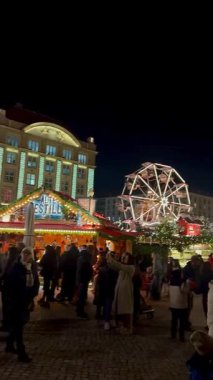 Yanıp sönen ışıklar ve büyük, süslü bir Noel ağacı Almanya 'nın Dresden kentindeki hareketli Sihirli Noel pazarını aydınlatıyor. Yüksek bir dönme dolap.. 