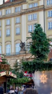 Dresden, Almanya - 05 Aralık 2024: Dresden 'in Noel pazarında yeşillik ve tatil süslemeleri ile süslenmiş şenlikli ahşap tezgahlar yer alıyor. Kış kıyafetleri giymiş, çeşitli yaşlarda insanlar.