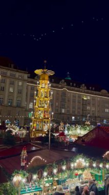 Yanıp sönen ışıklar ve büyük, süslü bir Noel ağacı Almanya 'nın Dresden kentindeki hareketli Sihirli Noel pazarını aydınlatıyor. Yüksek bir dönme dolap.. 