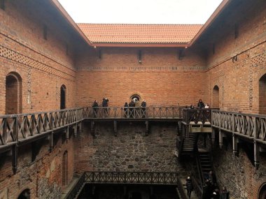 Trakai Kalesi 'nin Litvanya' daki avlusunda kırmızı-kahverengi tuğla duvarlar ve üst kat boyunca uzanan kiremitli ahşap kaldırımlar bulunuyor. Duvarlar küçük, kemerli pencereler ve dekoratif tuğla desenlerle çevrili.