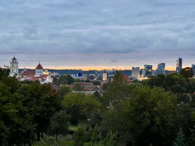 Litvanya, Vilnius 'un panoramik manzarası tarihi mimari ve modern gökdelenlerin bir karışımını sergiliyor. Şehir manzarasında geleneksel kırmızı çatılı binalar ve çağdaş yüksek binaların yanı sıra önde gelen kilise kuleleri yer alıyor..