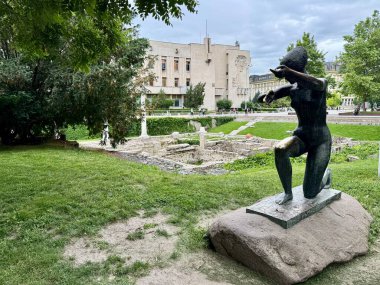 Diz çökmüş bir insan figürünün heykeli Bulgaristan 'ın Filibe kentinde yer alıyor. Heykel, bakımlı çimlerle çevrili taş bir heykel üzerinde duruyor. Arka planda, antik taş kalıntıları görülebilir.