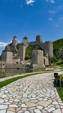 Sırbistan 'daki Golubac Kalesi Tuna Nehri' nin yanındaki kayalık bir tepeye tünemiş durumda. Ortaçağ yapısı, nehrin sakin sularına güzel yansıyan, konik çatıları ve taş duvarları olan birden fazla kuleyi sergiliyor..
