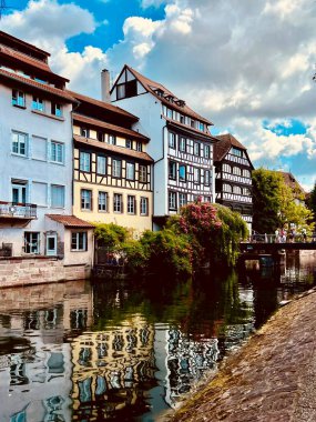 Fransa 'nın Strazburg bölgesindeki Petite France bölgesinde yarı keresteli evler, sakin bir kanal oluşturur. Koyu renk tahta kirişleri ve sayısız penceresi olan cepheler. Sakin su yapıları yansıtır. Nehir kıyılarını birbirine bağlayan küçük bir köprü.