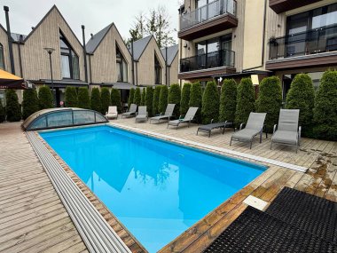 Palanga 'daki modern yerleşim bölgesinde avluda ortak bir yüzme havuzu bulunmaktadır. Uzun yeşil çalılar çevre boyunca doğal mahremiyet sağlar. Mimarlık ve peyzaj eğlence ve rahatlığa odaklanıyor. modern eğlence mimarisi.