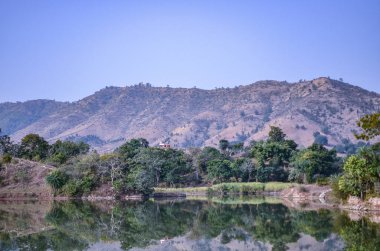 Udaipur 'dan Kumbalgarh Kalesi, Rajasthan, Hindistan' a giden kayalık arazide kıvrılan tatlı su nehirinin manzarası.