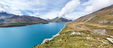Mountain road winding along lake Lac du Mont Cenis, Savoie, Auvergne-Rhone-Alpes, France, Europe.      