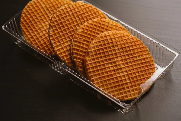 Galletas de oblea con caramelo en un sustrato transparente sobre fondo negro — Foto de Stock