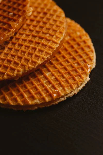 Waffeln mit Karamell auf schwarzem Hintergrund in Nahaufnahme — Stockfoto