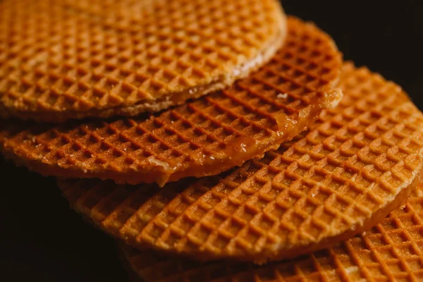 Waffeln mit Karamell auf schwarzem Hintergrund in Nahaufnahme — Stockfoto