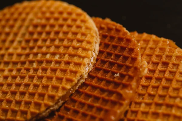 Waffeln mit Karamell auf schwarzem Hintergrund in Nahaufnahme — Stockfoto