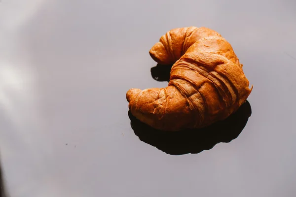 Frisches Croissant aus dem Blätterteig auf schwarzem Hintergrund — Stockfoto