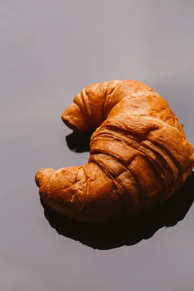 Frisches Croissant aus dem Blätterteig auf schwarzem Hintergrund — Stockfoto