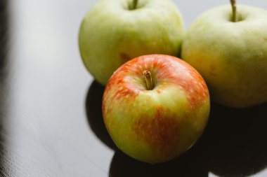 karanlık bir arka plan üzerinde birkaç taze olgun elma