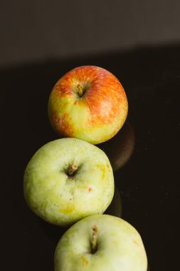 karanlık bir arka plan üzerinde birkaç taze olgun elma