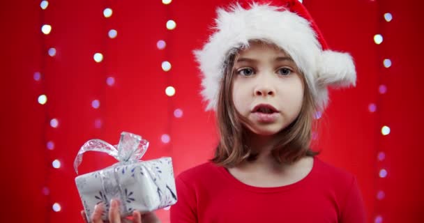 戴着圣诞红礼帽的可爱女孩带着礼物 — 图库视频影像