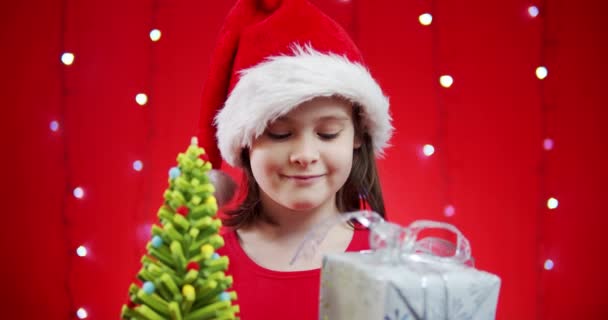 戴着圣诞红礼帽的可爱女孩带着礼物 — 图库视频影像