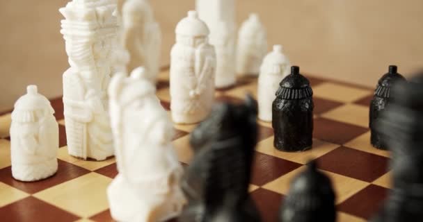 Piezas de ajedrez en blanco y negro sobre un tablero de ajedrez de madera — Vídeos de Stock