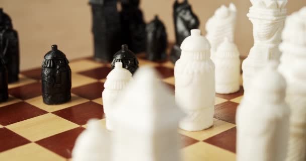 Piezas de ajedrez en blanco y negro sobre un tablero de ajedrez de madera — Vídeos de Stock