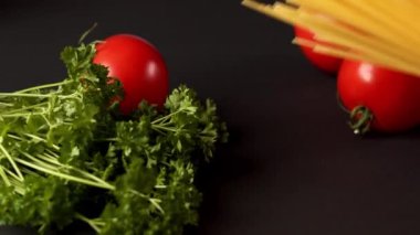 Siyah arka planda maydanozlu domates ve makarna.