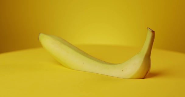 Roterende verse banaan op gele achtergrond — Stockvideo