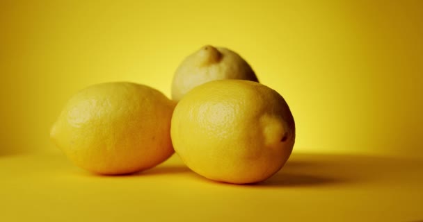 Limões frescos rotativos sobre um fundo amarelo — Vídeo de Stock