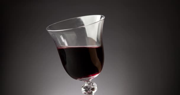 Rode wijn in een glanzend glas op een zwarte achtergrond — Stockvideo