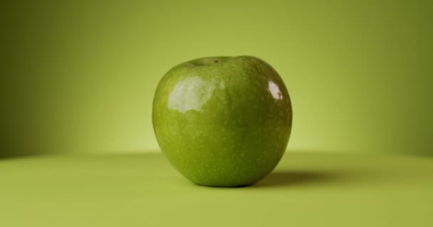 Deliciosa maçã verde rotativa sobre um fundo colorido — Vídeo de Stock