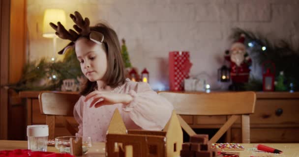 Mignonne fille construire et décorer pain d'épice maison de Noël — Video
